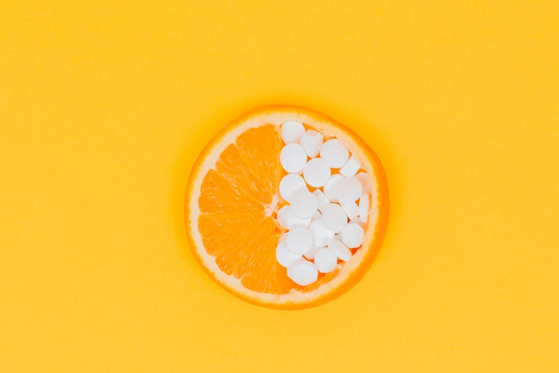 Vitamin tablets laid on top of half an orange, representing immune health